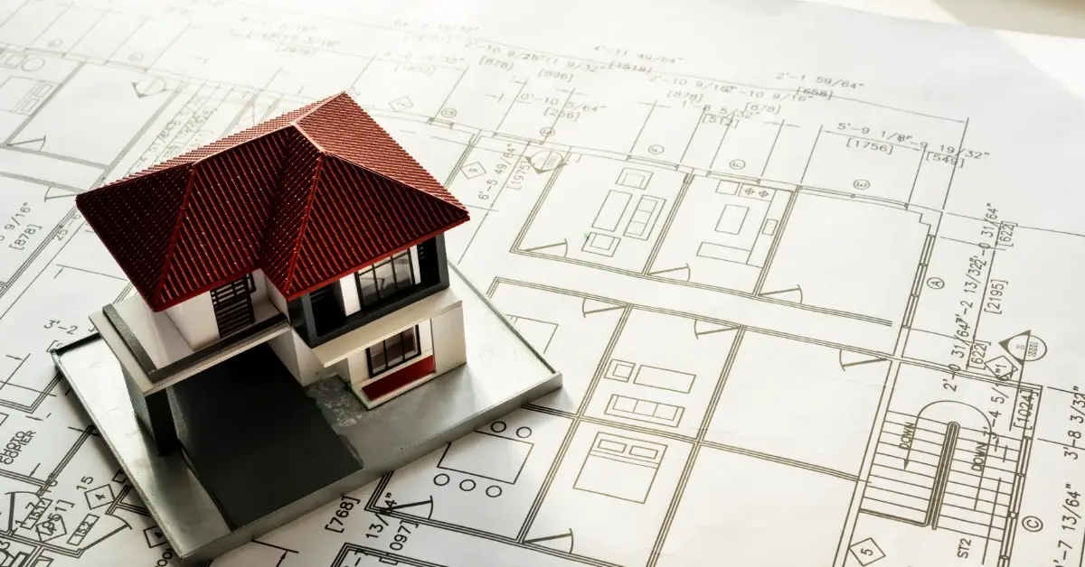 House model on architectural plans representing property development and conveyancing process