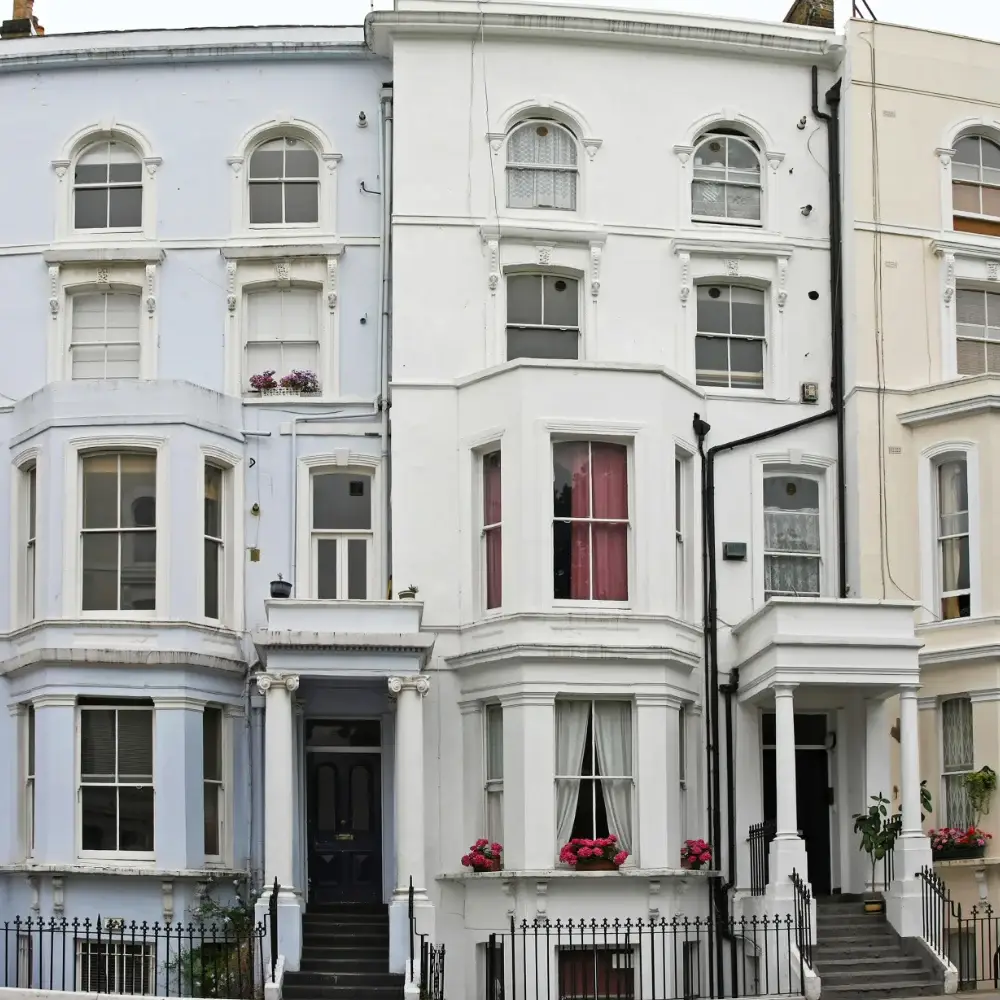 Victorian terraced houses in London with bay windows, white façades, front steps and black iron railings.